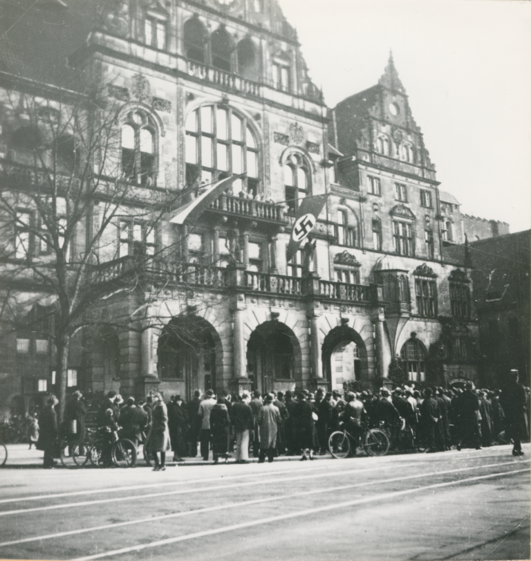 Auf dem Rathausbalkon wird am 6. März 1933 eine Hakenkreuzfahne gehisst.